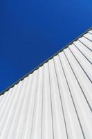 Textured white metal structures diagonally against a blue sky. photo