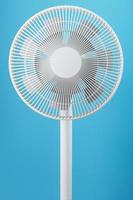 White modern electric fan for cooling the room on a blue background. photo