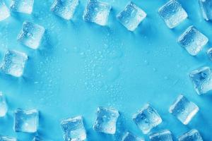 hielo hecho de cubos alineados con gotas sobre un fondo azul con espacio libre foto