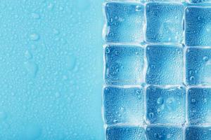 Ice made of cubes lined up with drops on a blue background photo