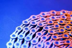 The texture of a shiny bicycle chain with a bluish-purple backlight photo