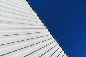 Textured white metal structures diagonally against a blue sky. photo