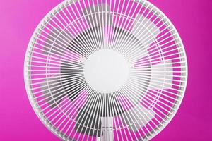 White modern electric fan for cooling the room on a pink background. photo