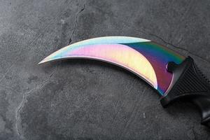 A dagger with a steel blade with a gradient color on a black background. photo