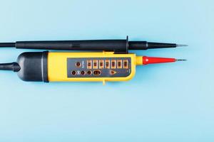 Yellow tester for step-by-step indication of voltage in an electrical circuit on a blue background. photo