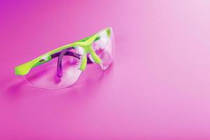 Transparent polycarbonate safety glasses on a pink background photo