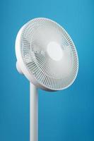 A high-tech white electric fan with a modern design for cooling the room on a blue background photo