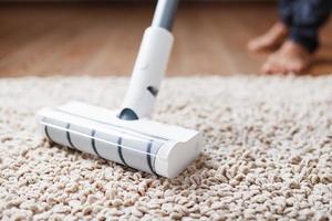 A cordless vacuum cleaner cleans the carpet in the living room with the bottom of the legs. photo