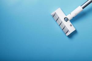 White vacuum cleaner brush on a blue background, top view. Cleaning concept photo