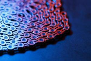 la textura de una cadena de bicicleta brillante con retroiluminación azul-púrpura foto