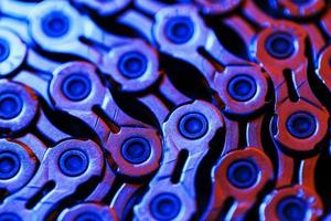 The texture of a shiny bicycle chain with a bluish-purple backlight photo