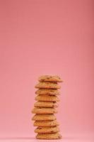 Oatmeal cookies with chocolate are stacked on a pink background. photo