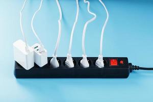 Electric mains filter with inserted white plugs of electrical appliances on a blue background. photo