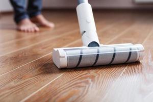 Turbo brush cordless vacuum cleaner close-up cleans the parquet in the house. photo
