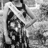 Indian couple posing for maternity baby shoot. The couple is posing in a lawn with green grass and the woman is falunting her baby bump in Lodhi Garden in New Delhi, India - Black and White photo