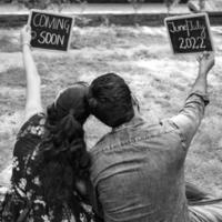 pareja india posando para una sesión de fotos de maternidad. la pareja está posando en un césped con hierba verde y la mujer está faluntando su panza en el jardín de lodhi en nueva delhi, india - blanco y negro