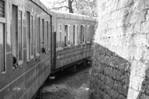 Toy Train moving on mountain slope, beautiful view, one side mountain, one side valley moving on railway to the hill, among green natural forest.Toy train from Kalka to Shimla in India-Black and White photo