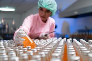 Product quality control staff at the fruit juice production line Perform product quality checks To ensure that the products produced are of good quality photo