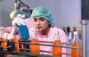 Product quality control staff at the fruit juice production line Perform product quality checks To ensure that the products produced are of good quality photo