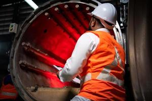 el ingeniero jefe de la planta mecánica realiza la inspección del túnel de la máquina de esterilización. para comprobar el estado de funcionamiento de la máquina para estar listo foto