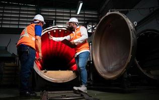 ingeniero jefe de una planta mecánica inspeccionando y explicando el mantenimiento de la máquina al mecánico foto