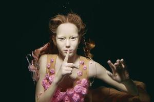 Young redhead girl in dress made of roses underwater photo