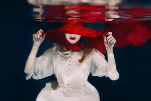 Woman in red hat and red scarf underwater photo