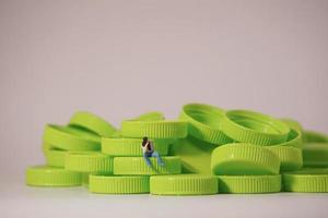 figura de hombre sentada en una tapa de plástico. reciclar el concepto de material. foto