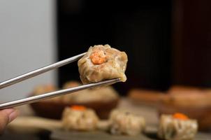 Close Up Chinese steamed dimsum or dim sum, on chopsticks, traditional cuisine photo