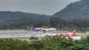 phuket, thaïlande 2 décembre 2016 - airbus 330 thai airways, boeing 767 asia atlantic airlines à apron, et airbus 320 airasia accélèrent sur la piste mouillée de l'aéroport de phuket. temps pluvieux, images hdr video