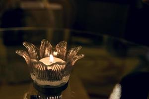 candle in a glass vase on glass table photo