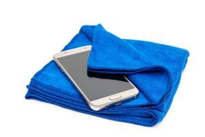 Pantalla sucia de limpieza de smartphones con tela de microfibra azul, aislada en fondo blanco foto
