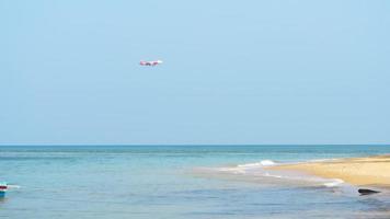 phuket, thaïlande 13 novembre 2019 - airasia airbus a320 s'approchant de l'océan et des bateaux de pêcheurs à longue queue garés sur la plage de mai khao près du village de pêcheurs de l'île de phuket. Thaïlande video