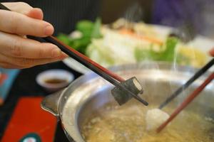 chopsticks holding meat ball in restaurant photo