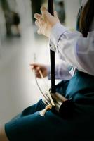 Girl student is playing thai music instrument,treble fiddle,violon soprano photo