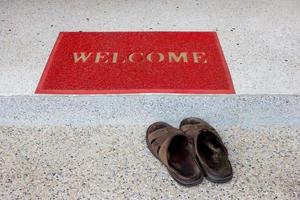 red welcome doormat on staircase and old sandals photo