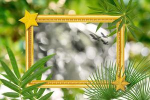 Green leaves pattern with antique golden picture frame on natural bokeh blurred background, autumn plant leaf photo