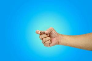 male hand holding coin,saving money concept of business concept,isolated on blue background photo