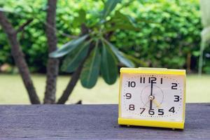 Closeup alarm yellow clock, 6 o'clock with Natural bokeh background photo