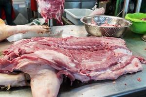 Carne de cerdo fresca en mesa de acero inoxidable en el mercado, Tailandia foto