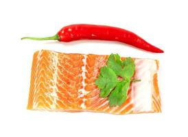 Piece of fresh salmon fillet sliced with coriander leaves and red pepper isolated on white background photo