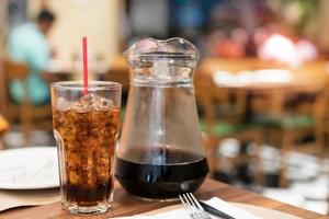 agua de cola y hielo en vaso con tarro en restaurante foto