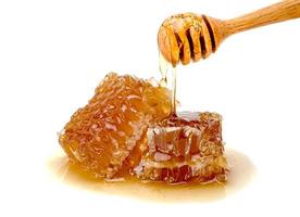 Fresh Honeycomb slice and wooden honey dipper isolated on white background photo