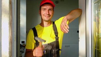 Portrait of a house repair and construction master with a close-up tool. A builder with a hammer in the interior of the house. Carpenter services, setup and installation video