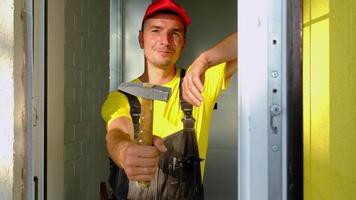 retrato de un maestro de reparación y construcción de casas con una herramienta de primer plano. un constructor con un martillo en el interior de la casa. servicios de carpinteria, montaje e instalacion video