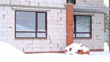 un incompiuto Casa fatto di poroso mattone sta sotto il neve nel inverno - incompiuto costruzione, crisi, di stagione opera. esterno decorazione di il Casa a un' freddo temperatura video