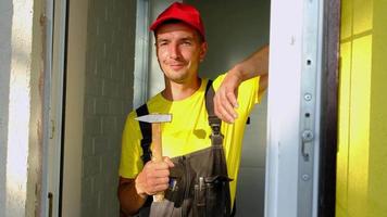 Portrait of a house repair and construction master with a close-up tool. A builder with a hammer in the interior of the house. Carpenter services, setup and installation video