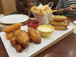 pollo frito y papas fritas y pan de ajo en la mesa foto