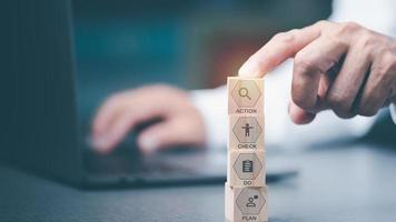 Entrepreneur points to wooden blocks showing concepts of planning strategies in professional work, divided into steps, plan, Do, check, Action, and also brainstorming for analysis with the team. photo