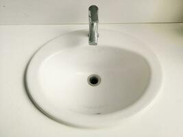 White sink and silver faucet with water drop marks, old and dull image. photo